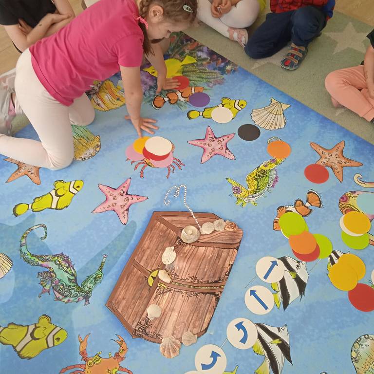 Dzieci uczące się angielskiego przez zabawę na kolorowym dywanie edukacyjnym